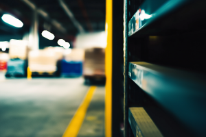Blurred interior warehouse scene with shelves on the right, pallets and crates in the background.