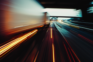 Long-exposure view of a trailer on the highway, creating bright orange and white light trails.