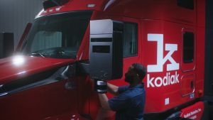 Groundbreaking 2025 Milestone: Kodiak Driverless Trucks Revolutionize Permian Oilfield Logistics 7 Technician removing a Kodiak SensorPod module from the mirror of a red autonomous truck in a maintenance bay.