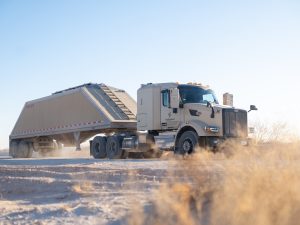 Groundbreaking 2025 Milestone: Kodiak Driverless Trucks Revolutionize Permian Oilfield Logistics 4 Autonomous frac sand truck equipped with Kodiak Driver hauling a trailer along a dusty lease road in the Permian Basin.