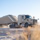 Autonomous frac sand truck equipped with Kodiak Driver hauling a trailer along a dusty lease road in the Permian Basin.