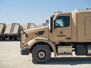 Groundbreaking 2025 Milestone: Kodiak Driverless Trucks Revolutionize Permian Oilfield Logistics 2 Side view of a tan frac sand truck parked on a yard with multiple sand trailers staged in the background.