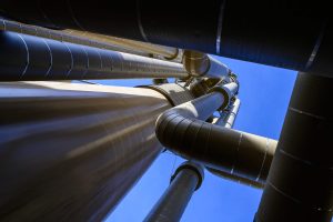 Texas Petroleum Theft Surge: 9 Critical Risks Driving a Dangerous Cargo-Tank Crackdown 4 Industrial midstream pipeline and facility infrastructure viewed from below against a blue sky.