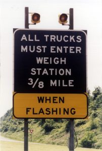 Texas CDL English Rule: 9 Critical Compliance Shifts for Drivers and Fleets 3 Roadside weigh station sign instructing commercial vehicles to enter when flashing.