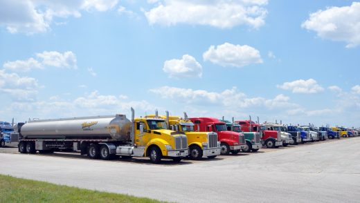 Full view of rows of fuel tanker trucks staged on an airfield tarmac in Texas.