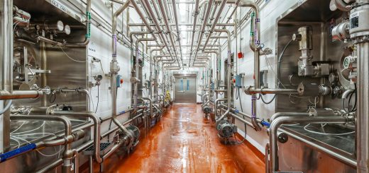 Stainless-steel dairy-processing pipes and raw-product tanks inside a Ninth Avenue Foods facility.