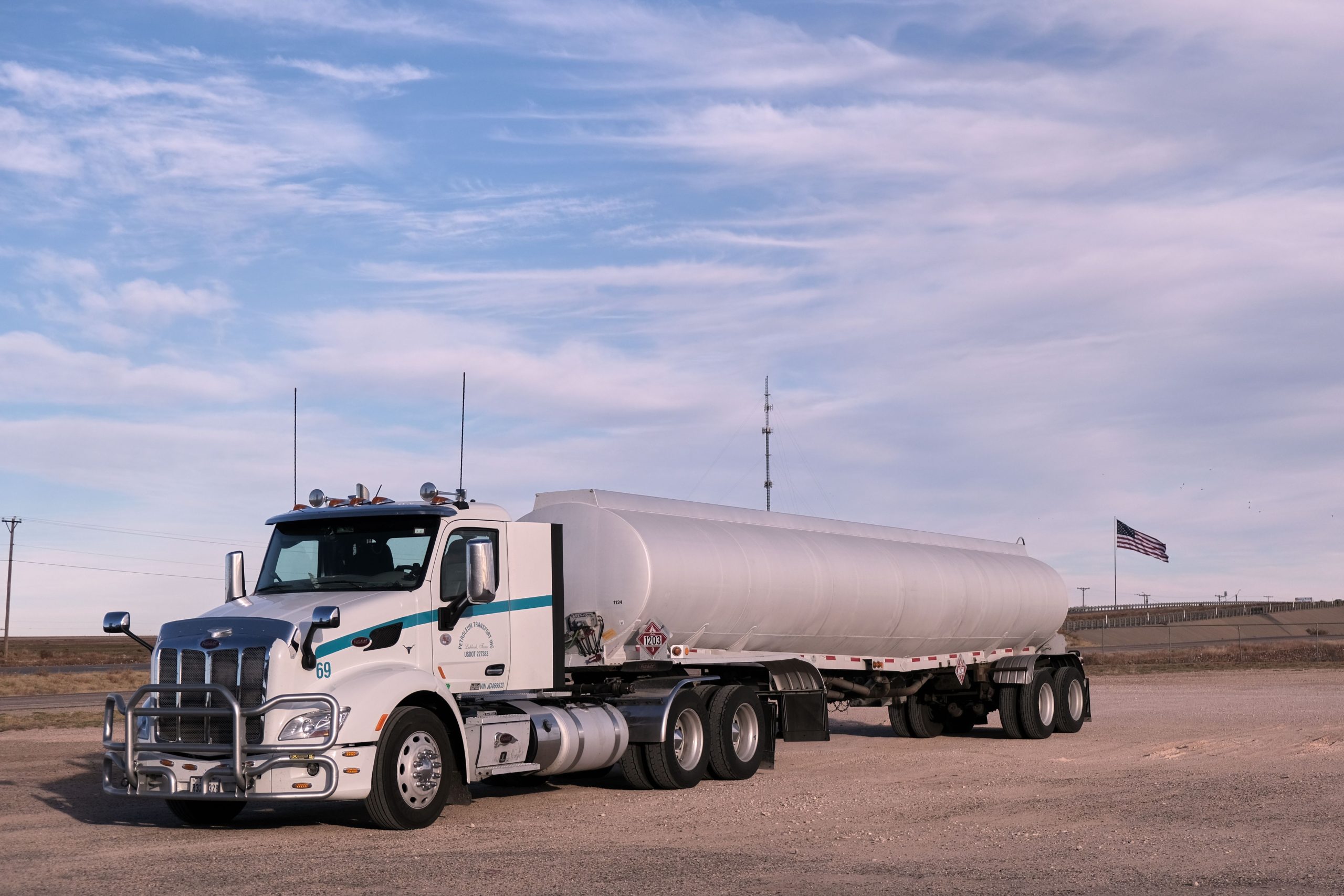 White tractor with a silver fuel cargo-tank trailer parked in a Texas landscape under clear skies