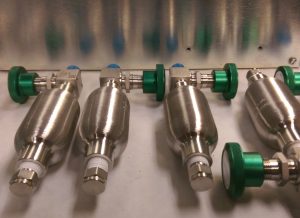 Canada Raises U.S. Gas-Container and Steel-Tank Tariffs to 50%, With Relief Still Available 4 Six silver gas-sample cylinders of different sizes, with valves and pressure gauges, against a gray background.