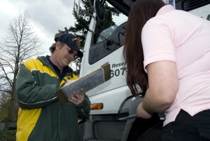 New DataQs Review Process: What Tank Fleets Need to Know 4 DMV representative writes on a clipboard while reviewing a pre-trip inspection checklist with a driver beside a truck.